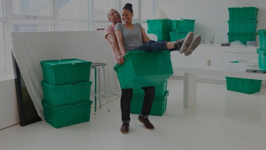 A happy couple playfully moving items with green QuickTotes moving totes in their Indianapolis, IN apartment.