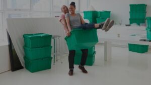 A happy couple playfully moving items with green QuickTotes moving totes in their Indianapolis, IN apartment.