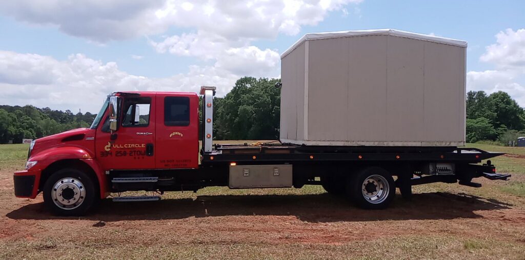 A covered container loaded onto a flatbed tow truck from Full Circle Towing and Recovery in Dothan, AL.