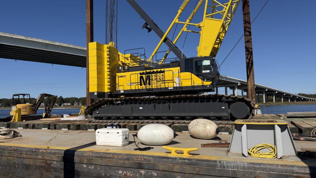 A large yellow crane on a Myrick Marine Contracting Corp. barge, ready for marine construction services in Norfolk, VA.