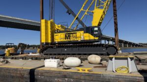 A large yellow crane on a Myrick Marine Contracting Corp. barge, ready for marine construction services in Norfolk, VA.