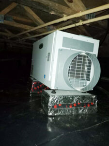 A dehumidifier installed on a black vapor barrier in a crawl space by Tidewater Home Improvement LLC in Hampton, VA.
