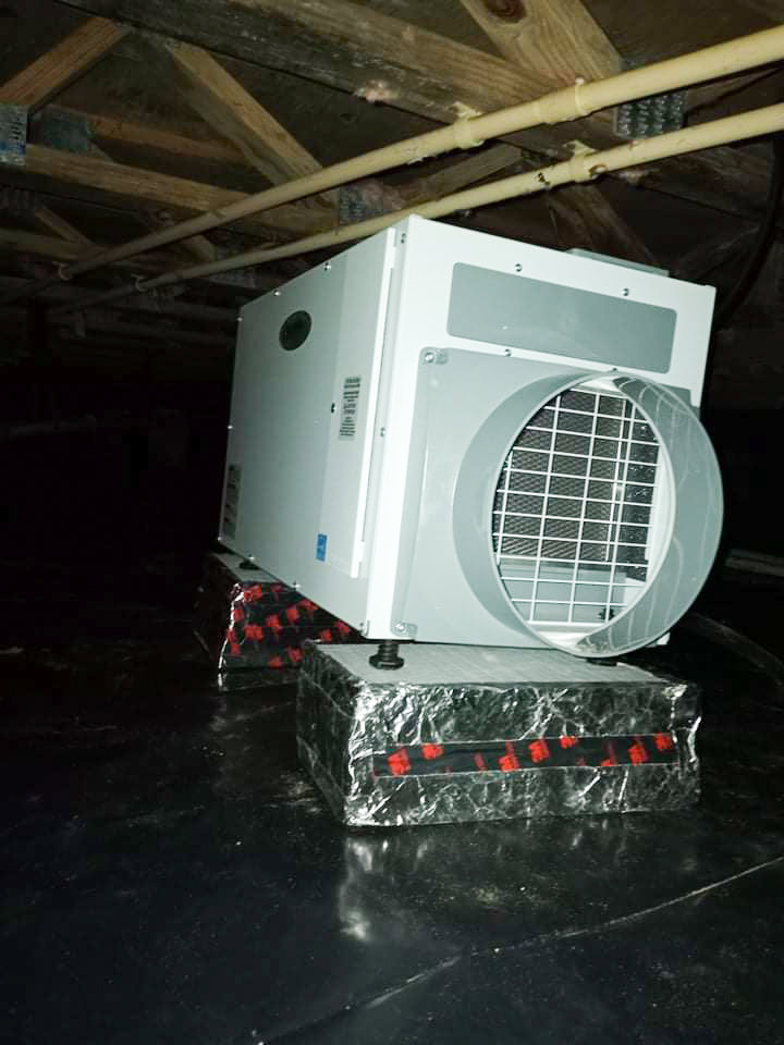 A dehumidifier installed on a black vapor barrier in a crawl space by Tidewater Home Improvement LLC in Hampton, VA.