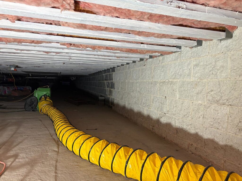 A crawl space being dried with large flexible ductwork for air movement by Mold Master Restoration in Jersey City, NJ