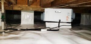 A crawl space with white vapor barrier and a dehumidifier installed by Tidewater Home Improvement LLC in Hampton, VA.