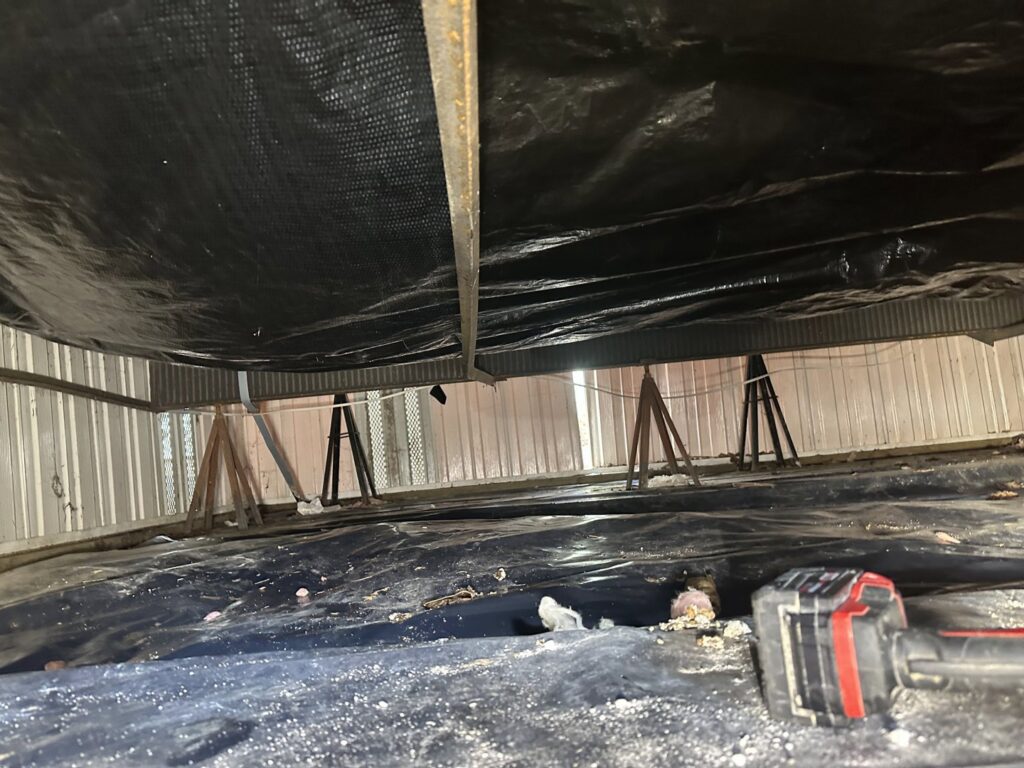 A crawl space with a black moisture barrier installed by Brothers Restoration for water damage prevention in Post Falls, ID.