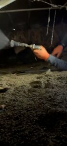 A technician performing mold or moisture treatment in a crawl space, part of water damage remediation by Healthy Interior Solutions in Fishers, IN.
