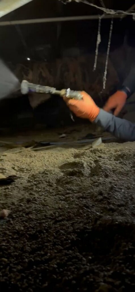 A technician performing mold or moisture treatment in a crawl space, part of water damage remediation by Healthy Interior Solutions in Fishers, IN.