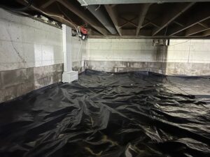 A crawl space with a black vapor barrier and an EZ Breathe system installed by EverDry Toledo in Toledo, OH.