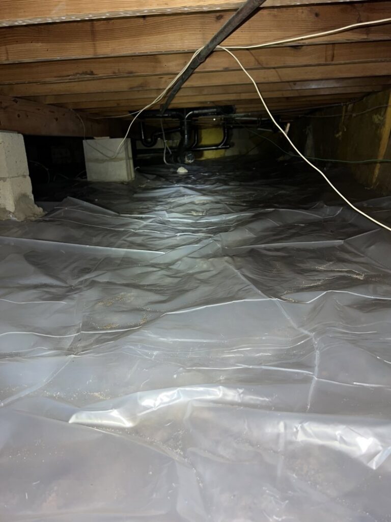 A crawl space with a newly installed vapor barrier for moisture control by New Method Restoration in Edison, NJ.