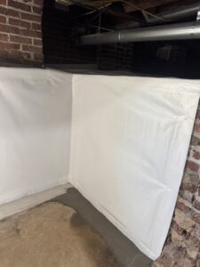 A crawl space wall covered with a white vapor barrier by Wetlock Waterproofing in Rock Hill, SC.