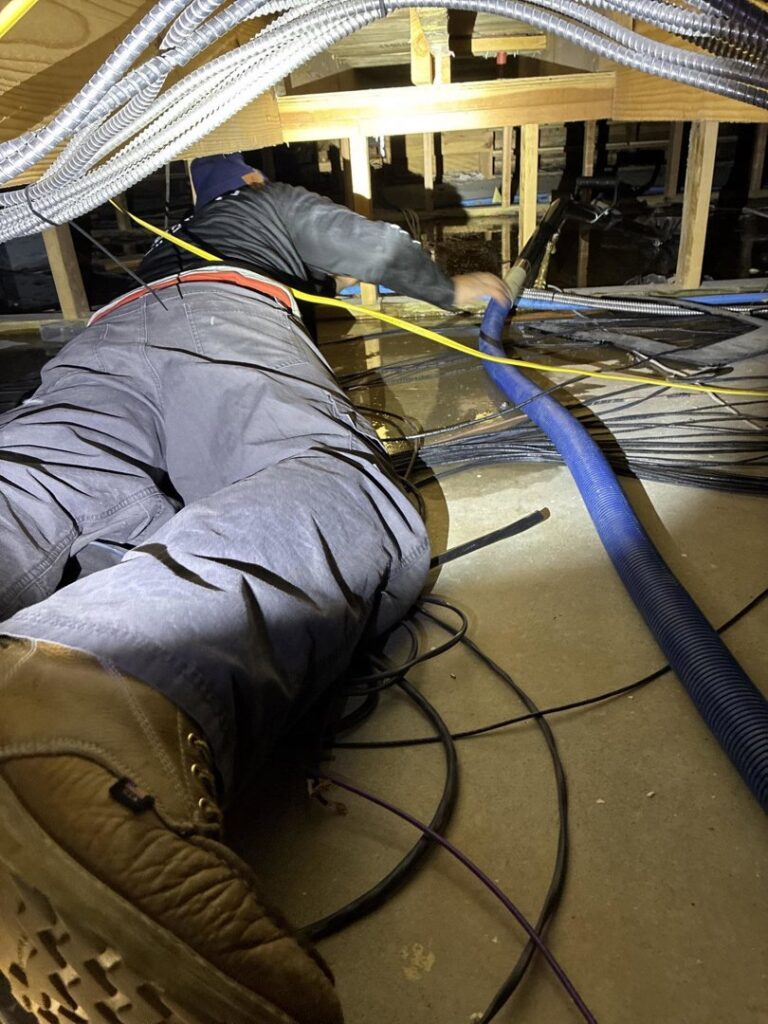 A technician performing water extraction in a tight crawl space during water damage restoration by TriForce Restoration in Moore, OK.