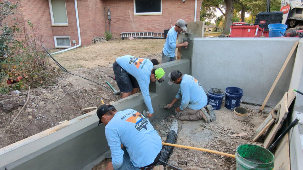 A crew of pool contractors applying concrete or plaster to a pool wall, showcasing expertise from Acapulco Pool and Spa LLC in Los Angeles, CA