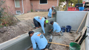 A crew of pool contractors applying concrete or plaster to a pool wall, showcasing expertise from Acapulco Pool and Spa LLC in Los Angeles, CA