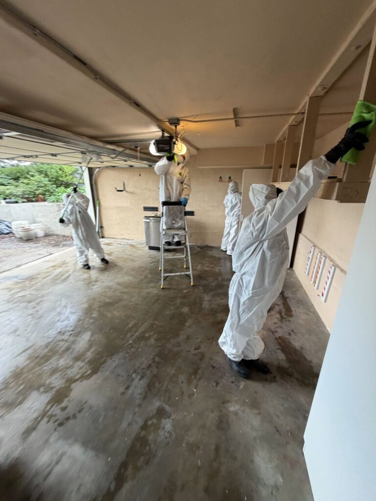 Servpro of Sandy crew in protective suits cleaning a garage after water damage in Sandy, UT.