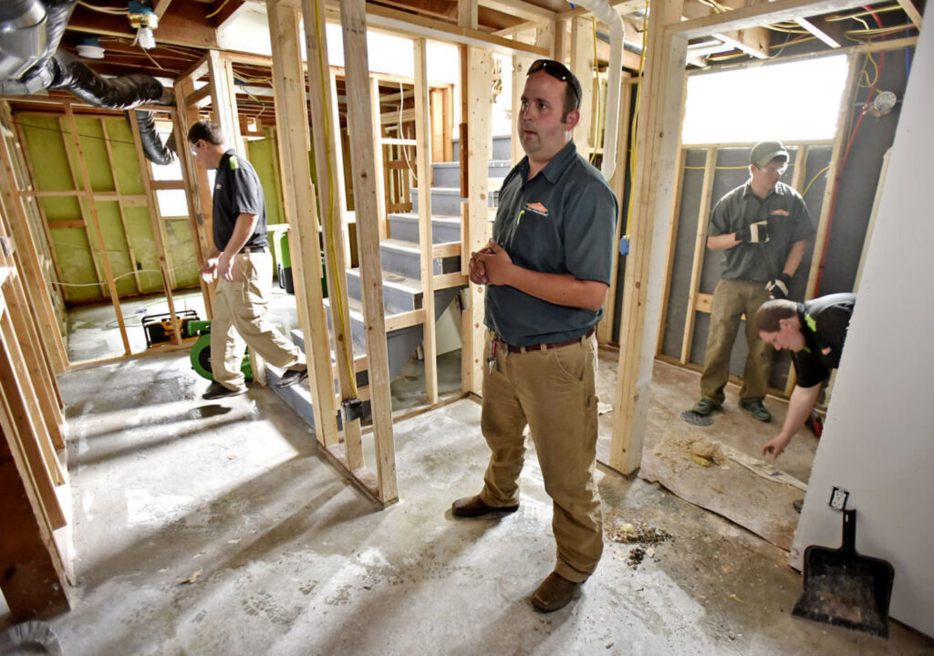 A water damage restoration crew removing damaged flooring in a basement during cleanup by Water Damage Pro in Minneapolis, MN