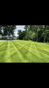 A spacious lawn meticulously mowed in a cross-hatch pattern, showcasing the precision of A & J Lawn Care LLC in Corsicana, TX.
