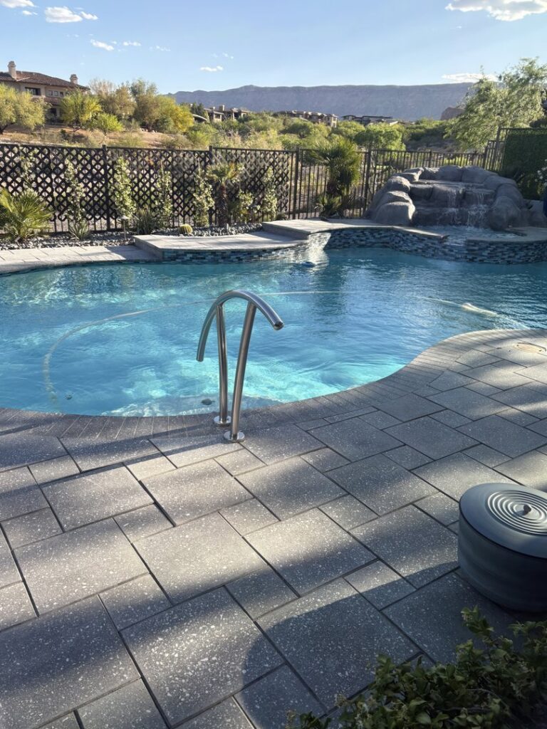A curved pool with a metal handrail and spacious patio by Laguna Pool & Spa and Landscaping in Las Vegas, NV