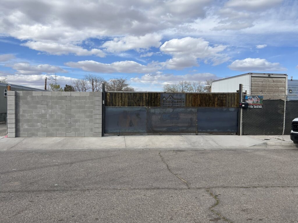 A custom gate featuring the Excellence Garage Doors LLC logo, installed as part of their gate access services in Albuquerque, NM.