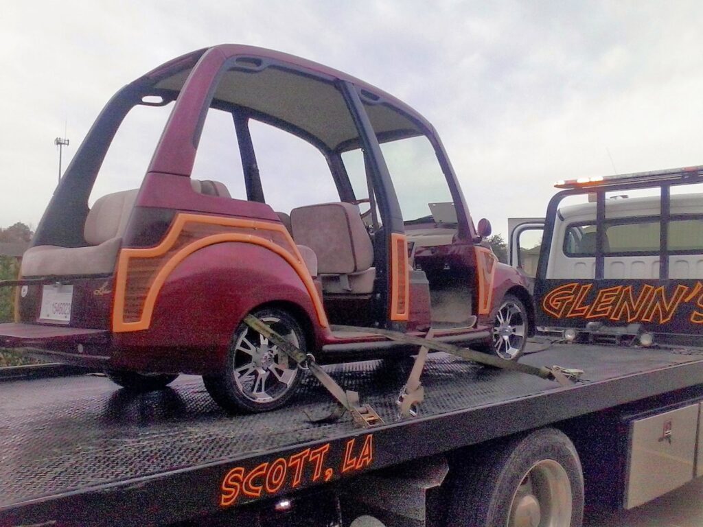 A custom golf cart loaded and secured on a flatbed tow truck from Glenn's Towing & Recovery Inc in Lafayette, LA.