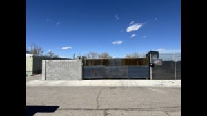 A custom metal gate with the business logo installed by Excellence Garage Doors LLC, providing gate access solutions in Albuquerque, NM.