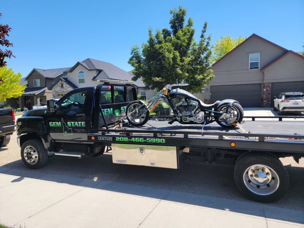 A custom motorcycle being transported on a flatbed tow truck by Gem State Towing and Recovery in Caldwell, ID.