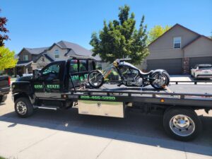 A custom motorcycle being transported on a flatbed tow truck by Gem State Towing and Recovery in Caldwell, ID.