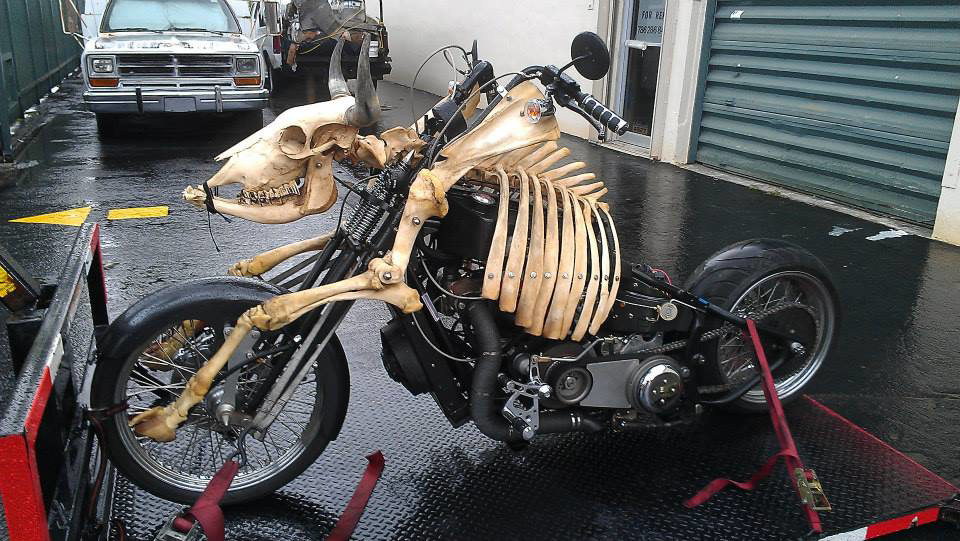 A custom skeleton-themed motorcycle securely loaded on a flatbed tow trailer by Motorcycle Rescue Inc. in Miami, FL.