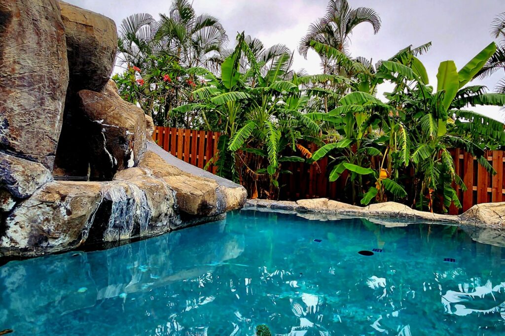 A custom-designed natural rock waterfall pool with tropical landscaping by NATURAL SALT POOLS LLC in Kailua, HI.