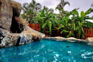 A custom-designed natural rock waterfall pool with tropical landscaping by NATURAL SALT POOLS LLC in Kailua, HI.