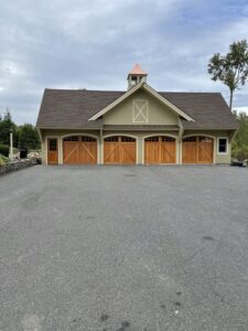 A beautiful residential building featuring four custom wooden garage doors, installed by RidgeLine Overhead Garage Door of CT in Danbury, CT
