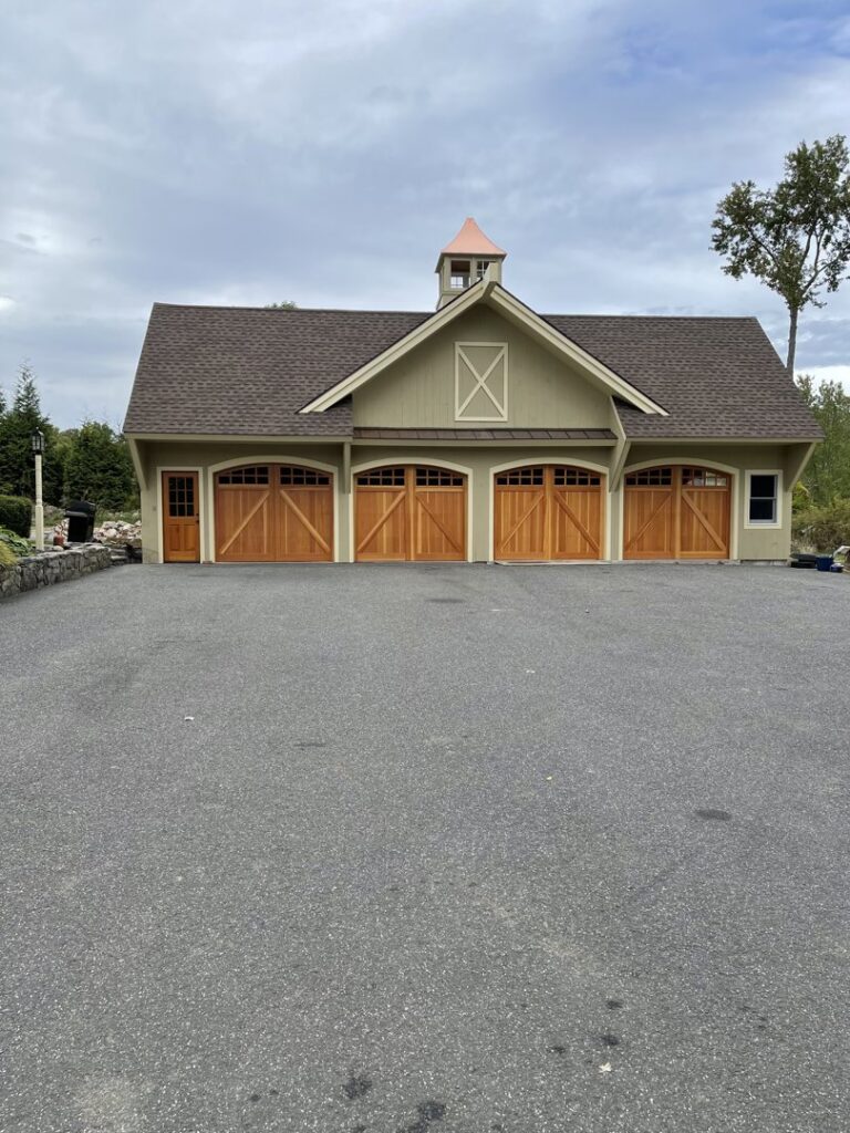 A beautiful residential building featuring four custom wooden garage doors, installed by RidgeLine Overhead Garage Door of CT in Danbury, CT