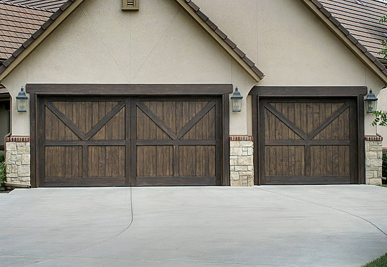 Two custom wooden garage doors with decorative hardware installed by Ultimate Garage Doors LLC in Olive Branch, MS.