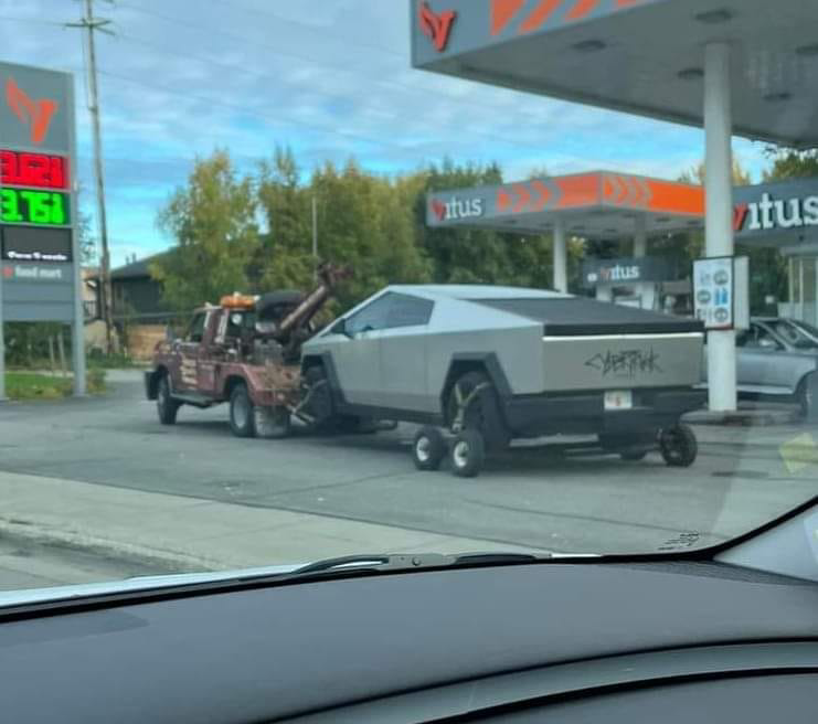 A Tesla Cybertruck being towed by a classic wrecker truck from Geely Towing in Fargo, ND.