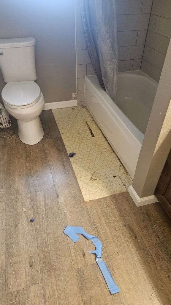 A bathroom with damaged flooring requiring water damage restoration by Harbaugh Restoration in Vancouver, WA.