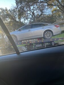 A damaged car bumper on the bed of a tow truck, indicating accident recovery by AB Towing & Transport in San Antonio, TX.