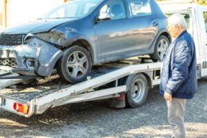 A damaged blue car being loaded onto a flatbed tow truck by Spokane Towing Services in Spokane, WA.