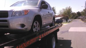 A heavily damaged car being recovered on a flatbed tow truck at night by Baltimore Towing Service LLC in Owings Mills, MD.