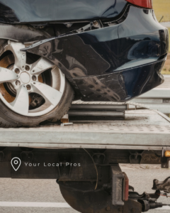 A damaged car being loaded onto a flatbed tow truck by Mechanix Unlimited Towing and Repair in Great Falls, MT.