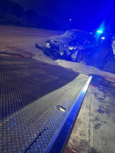 A severely damaged car at a roadside recovery scene at night by White's Wrecker Service in Memphis, TN.