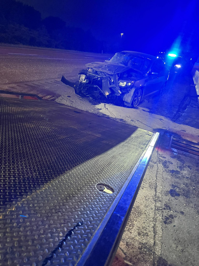 A severely damaged car at a roadside recovery scene at night by White's Wrecker Service in Memphis, TN.