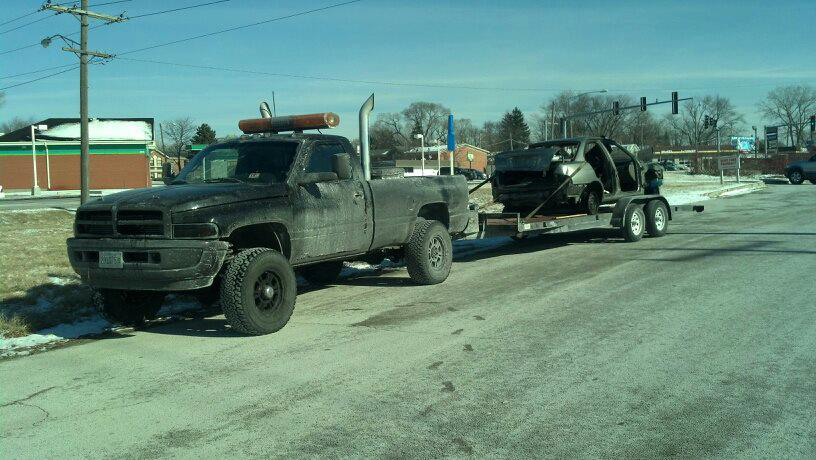 A damaged car being towed on a trailer by Jr & Sr towing and recovery in Waukegan, IL.