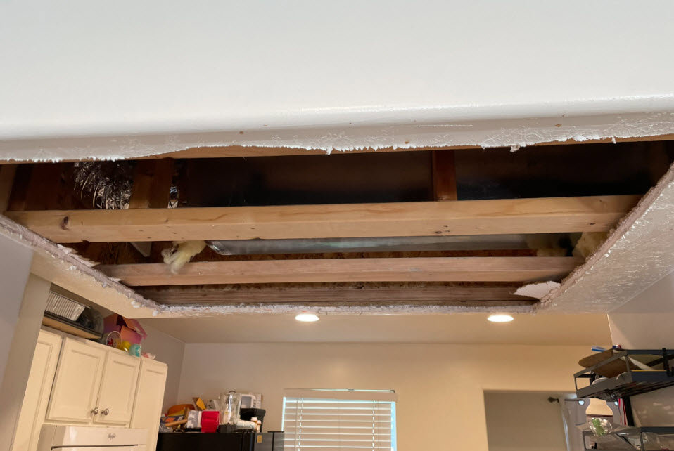 A damaged ceiling with exposed joists and ductwork, indicating water damage, being assessed by RestoPros of Salt Lake City, UT