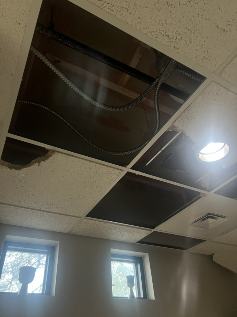 A damaged ceiling with removed tiles and exposed pipes, indicating water damage, handled by HTS Restoration in El Paso, TX.