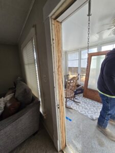 A severely damaged wooden door frame, likely from water damage, awaiting repair by Grand Rising Group in Mitchell, SD.