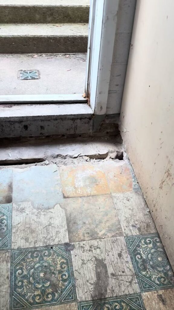 Damaged floor tiles near an entryway showing signs of water damage, a service provided by Waterdry Indiana in South Bend, IN
