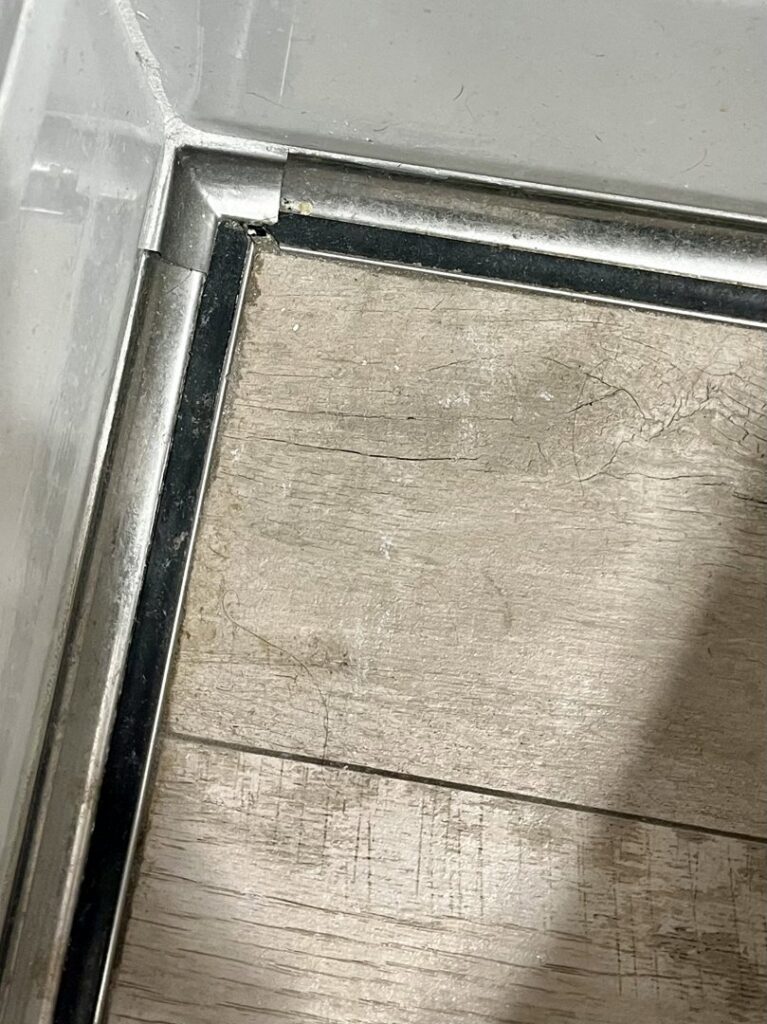 A close-up of a damaged floor trim corner with visible water stains and discoloration, indicating a water damage problem for Ciocca Cleaning & Restoration in Fort Wayne, IN.