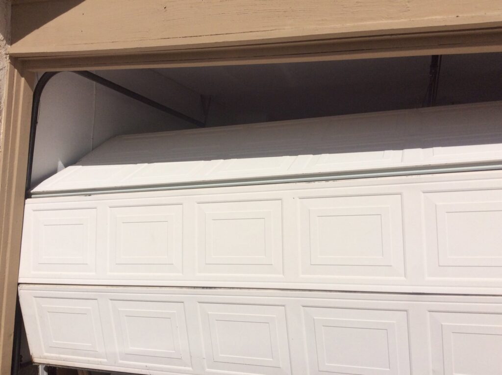 A residential garage door that is off its tracks and damaged, requiring repair by Garage Door Medics in Boise, ID.