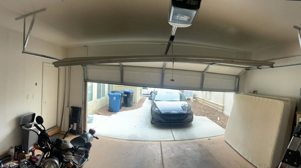 A damaged garage door off its tracks, requiring repair service from NV Pro Garage Doors in Las Vegas, NV.