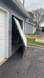 A damaged garage door requiring repair or replacement by Above All Garage Doors in Kansas City, KS.